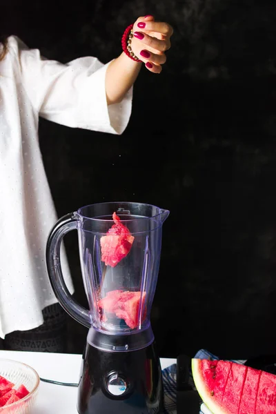 Женщина вставляет ломтики арбуза в блендер — стоковое фото