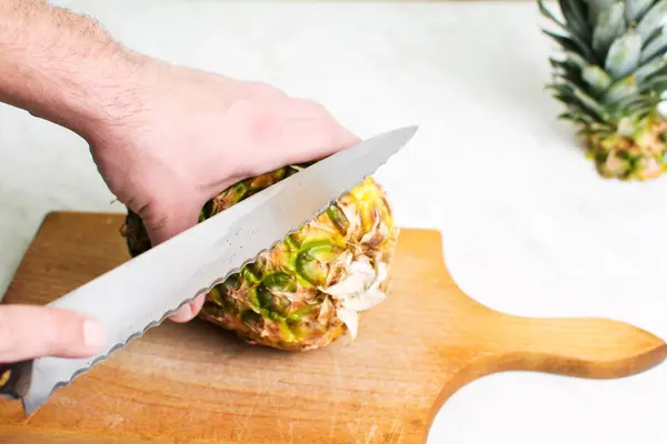 Man snijden ananas op een houten bord — Stockfoto