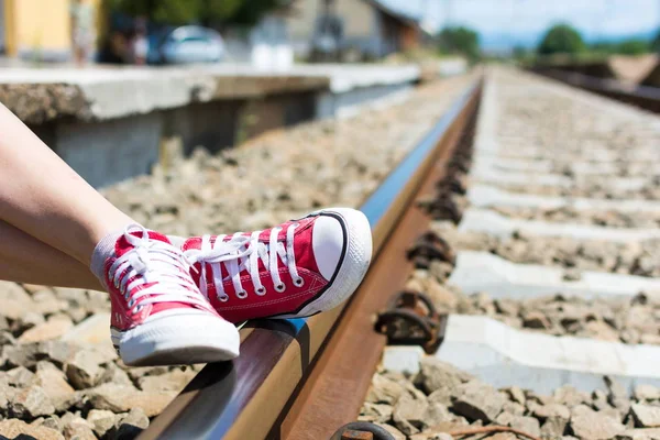 Dziewczyna stopy w czerwone trampki siedzi przez kolejowe — Zdjęcie stockowe
