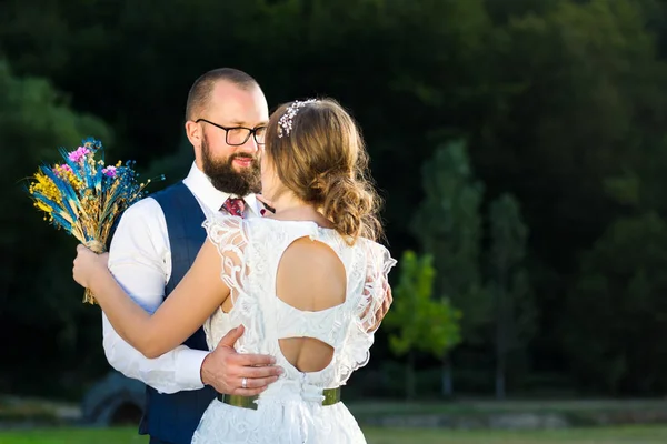 Bride and groom in romantic hug at sunset — Stock Photo, Image