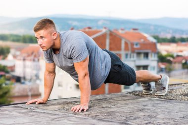 Man performing push ups on the rooftop clipart