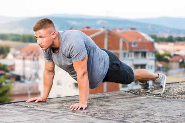 Man performing push ups on the rooftop — Stock Photo, Image