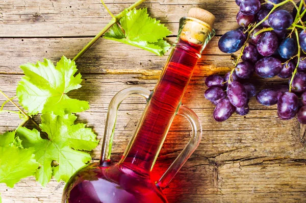 Vino rosso con uva su fondo rustico in legno — Foto Stock