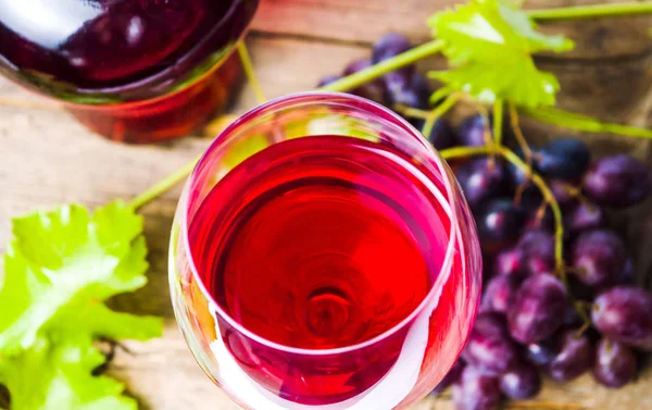 Skleničku červeného vína s hroznovým vínem na rustikální dřevěné pozadí — Stock fotografie