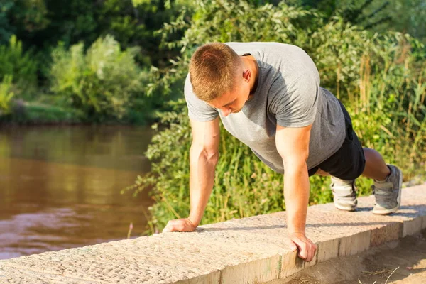 Člověk dělá push up u řeky — Stock fotografie