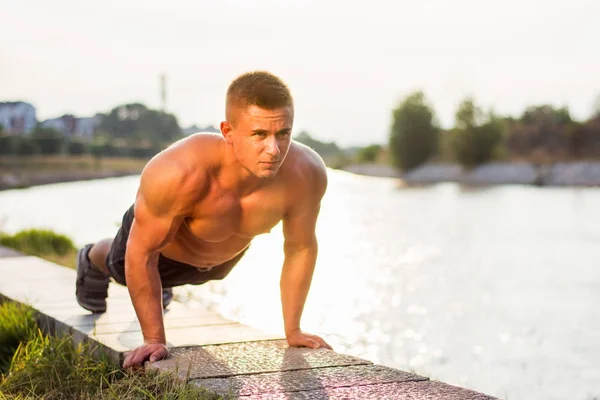 Člověk dělá push up u řeky — Stock fotografie