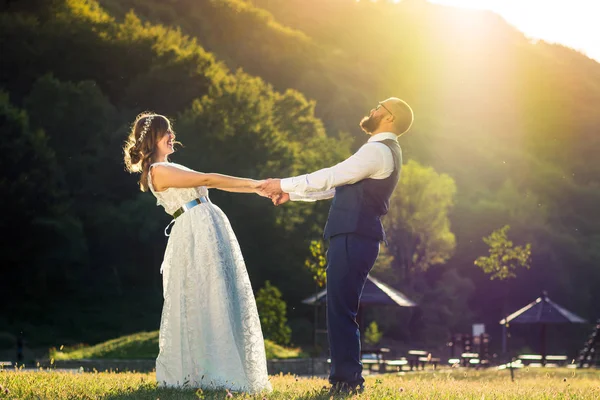 Braut und Bräutigam halten Händchen bei Sonnenuntergang — Stockfoto