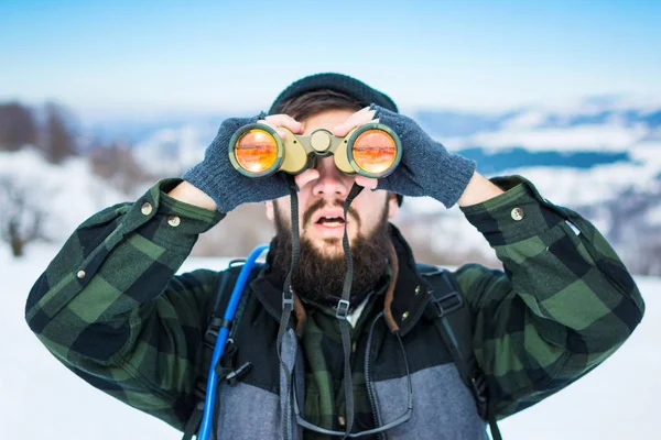 Hombre usando binoculares en la montaña cubierta de nieve — Foto de Stock