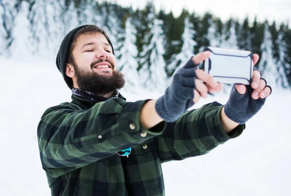 Skäggig man tar selfie på snöiga berget — Stockfoto