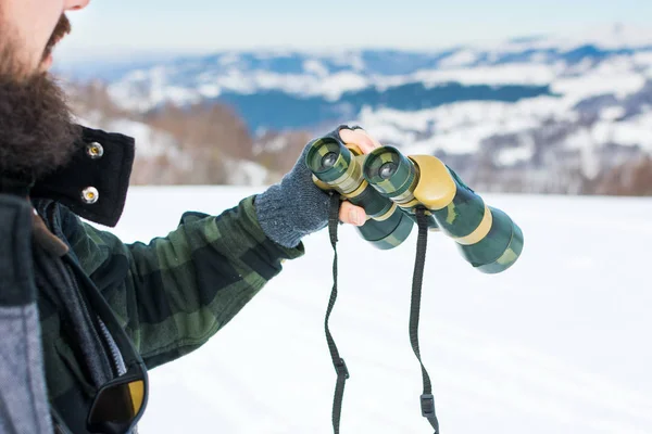 Hombre usando binoculares en la montaña cubierta de nieve — Foto de Stock