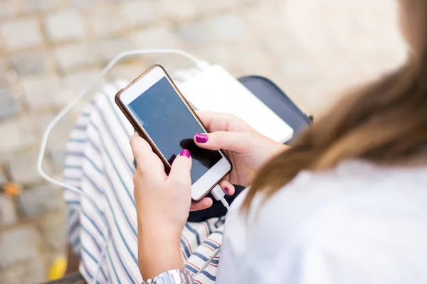 Fille en utilisant le téléphone tout en chargeant sur la banque d'alimentation — Photo