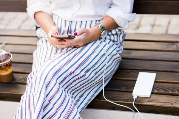 Fille en utilisant le téléphone tout en chargeant sur la banque d'alimentation — Photo