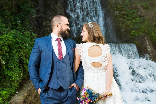 Весільна пара стоїть перед водоспадом — стокове фото