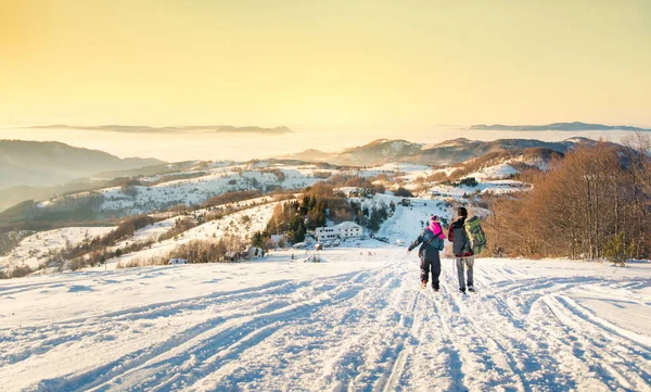 Casal andando pela montanha nevada na hora do pôr do sol — Fotografia de Stock