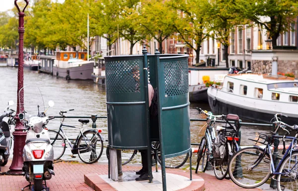 Man urinating in Amsterdam in a public urinal — Stock Photo, Image