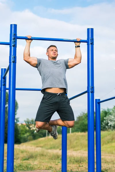 Man doing pull ups outdoors — Stock Photo, Image