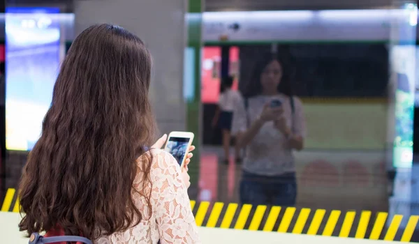 Fille à l'aide du téléphone en attendant le métro — Photo