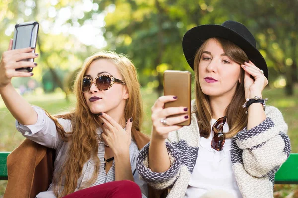 Meninas usando telefones em um banco — Fotografia de Stock