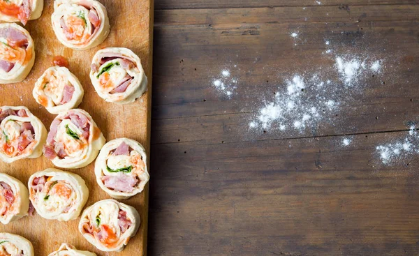 Crudo pIzza rollos de pastelería en una tabla de madera — Foto de Stock