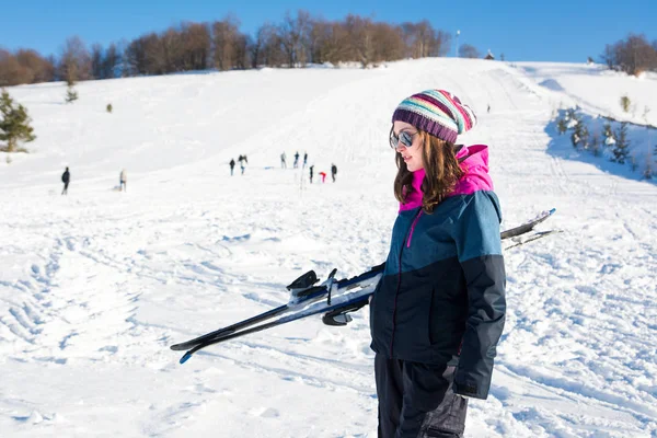 Menina segurando esquis em uma montanha nevada — Fotografia de Stock