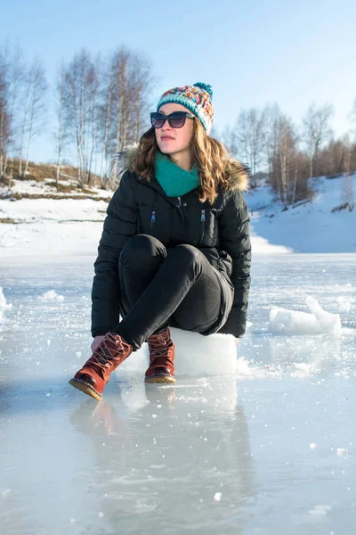 Fille assise sur un glaçon sur un lac gelé — Photo