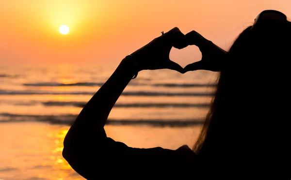 Girl making heart shape at seaside — Stock Photo, Image