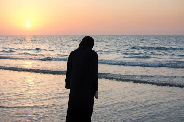 Woman in hijab standing on the beach