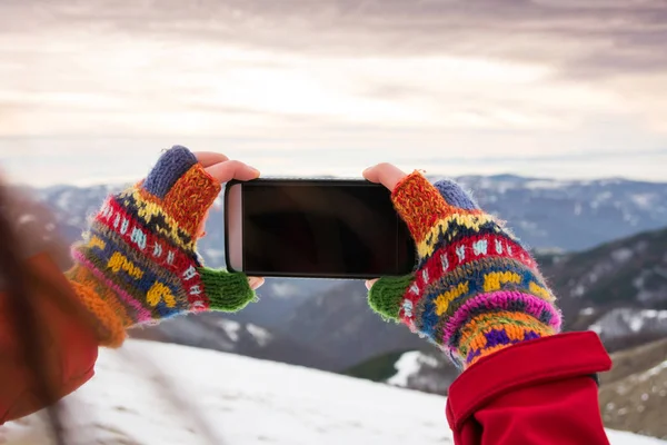Girl taking picture of winter scenery with a smart phone