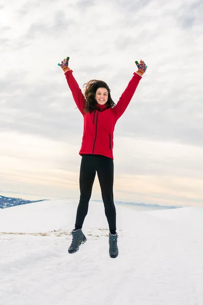 Fille heureuse sautant sur le sommet de la montagne couverte de neige — Photo