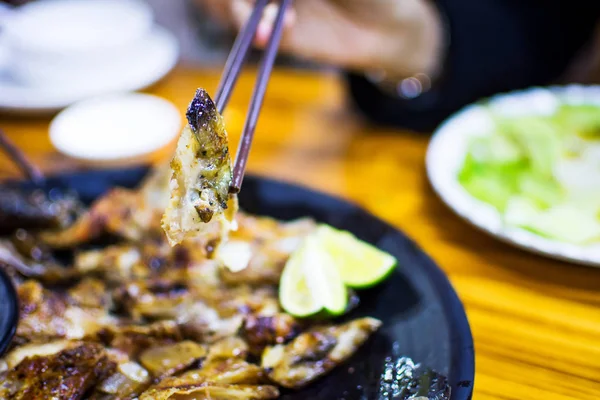 Palillos tomando cabeza de salmón asada de un plato —  Fotos de Stock