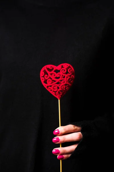 Perempuan memegang bentuk hati mengenakan sweater gelap — Stok Foto
