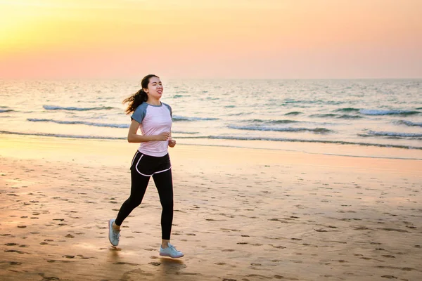 女孩在日落时在沙滩上跑 — 图库照片