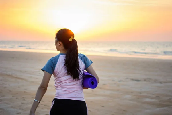 Mädchen mit Yogamatte am Strand — Stockfoto