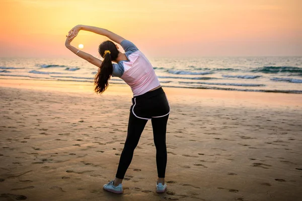 Fille exerçant sur la plage au coucher du soleil — Photo