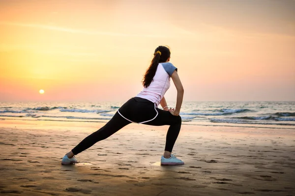 日落时分在沙滩上锻炼的女孩 — 图库照片