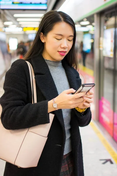 Flicka med telefon i väntan på tunnelbanan — Stockfoto