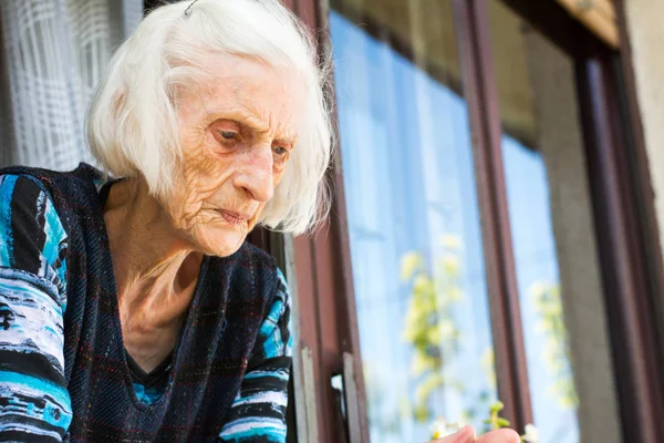 Senior kobieta patrząc z okna domu — Zdjęcie stockowe