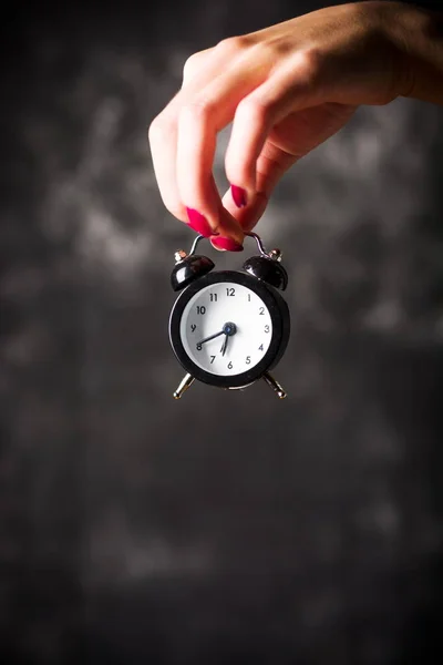 Mano femenina sosteniendo un pequeño reloj — Foto de Stock