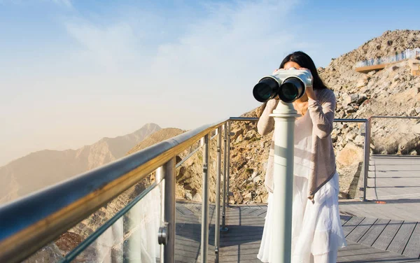 Mujer usando prismáticos públicos en la cima de la montaña — Foto de Stock