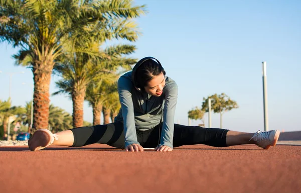 Mädchen wärmt sich vor dem Training auf Laufstrecke auf — Stockfoto