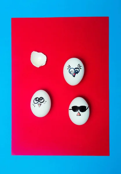 Ovos brancos com faces desenhadas sobre fundo vermelho — Fotografia de Stock