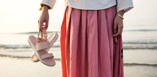 Дівчина тримає сандалі на пляжі — стокове фото