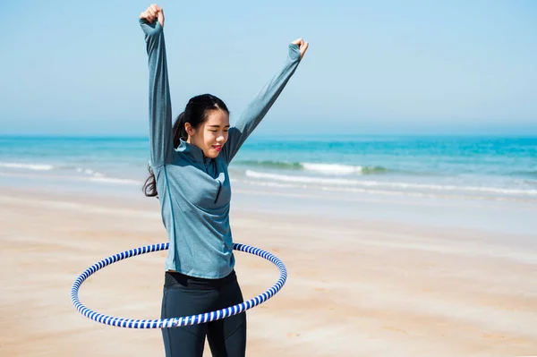 Gelukkige vrouw met hoelahoep op het strand — Stockfoto