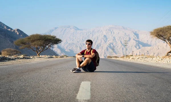 Man sitting on the empty dessert road — Stock Photo, Image