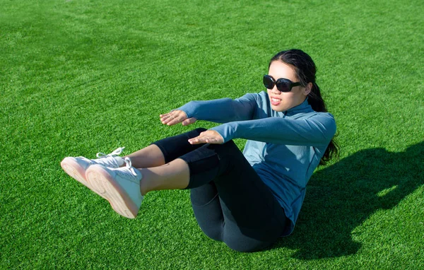 Meisje doet situps op het gras, outdoor training — Stockfoto