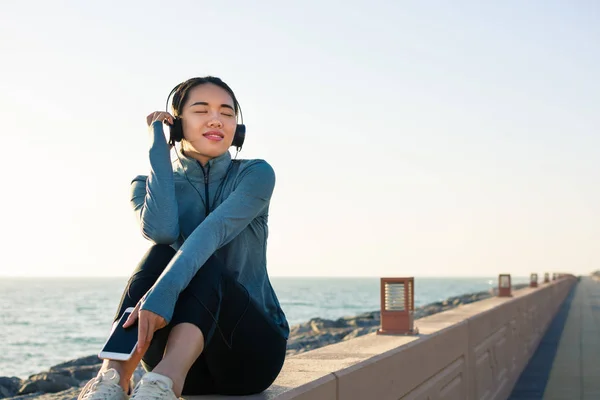 Dziewczyna, słuchanie muzyki, nad morzem i ciesząc się słoneczny dzień — Zdjęcie stockowe