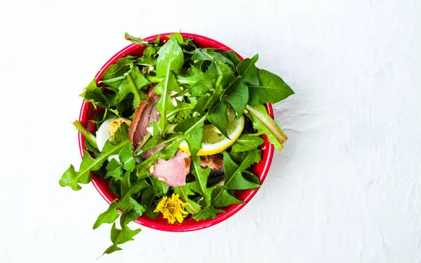 Ensalada de diente de león con carne de huevo y limón en un tazón —  Fotos de Stock