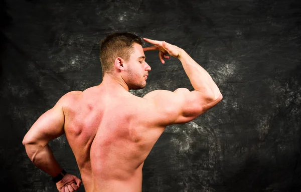 Bodybuilder flexing muscles against dark background — Stock Photo, Image