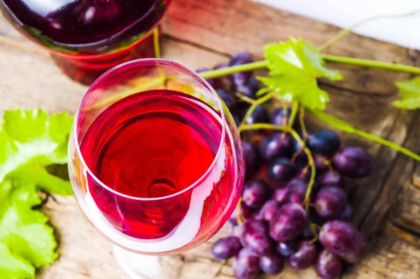 Skleničku červeného vína s hroznovým vínem na rustikální dřevěné pozadí — Stock fotografie