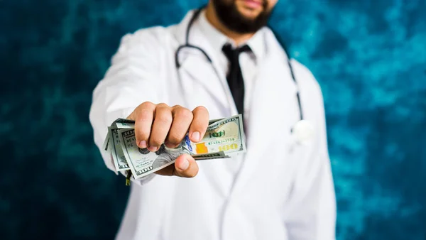 Доктор тримає доларові купюри крупним планом — стокове фото